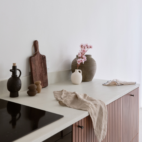 Wooden chopping board, ceramic vase, muslin cloth, small blossom tree and organic style salt and pepper shakers.